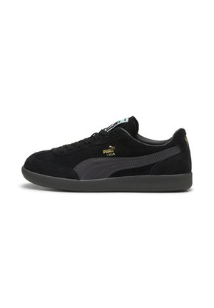 Baskets Puma Liga noires avec tige en daim, bande Puma grise, logo doré et semelle foncée, vues de profil sur fond blanc.