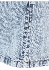 Tissu en denim bleu clair lavé à l'acide avec une couture centrale et un petit ourlet fendu, avec une couture beige en détail.