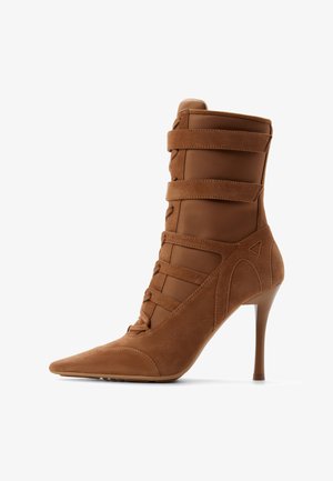 Brown suede high-heeled ankle boot with pointed toe, five horizontal straps, and a slim stiletto heel on a white background.