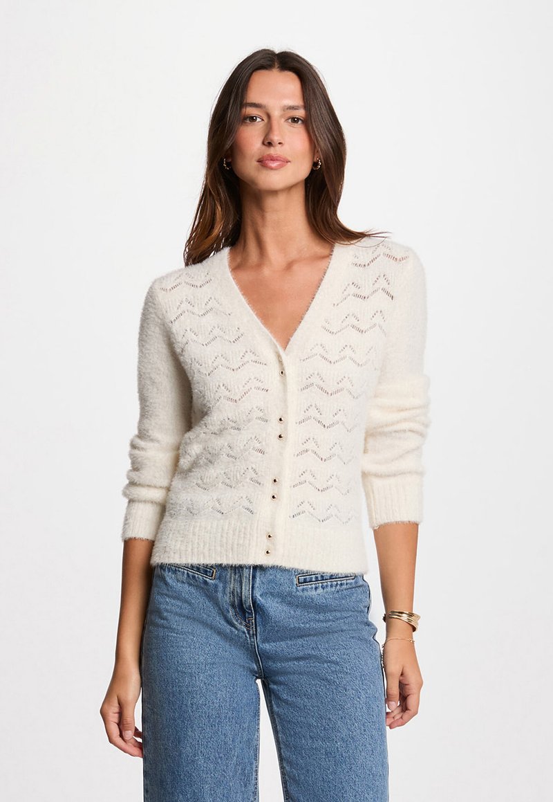 Cardigan lavorato a maglia avorio con scollo a V, maniche a tre quarti, motivo a zigzag e chiusura a cinque bottoni, realizzato in un materiale morbido e testurizzato.