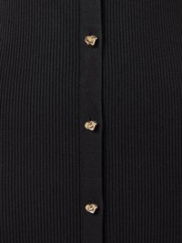 Μαύρο τοπ από ριμπ ύφασμα με χρυσά κουμπιά σε σχήμα καρδιάς στο κέντρο, τονίζοντας την υφή και το σχέδιο.