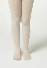 Beżowe rajstopy dziane z pionowymi prążkami, miękką teksturą i dopasowanym krojem, sięgające od talii do kostek.