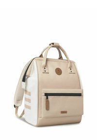 Beige Canvas-Rucksack mit weißen Akzenten, runder Oberseite, doppelten Griffen, verstellbaren Schulterriemen, Reißverschlussfronttasche und Logo-Patch.