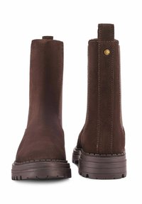 Para ciemnoniebieskich zamszowych botków z grubą gumową podeszwą, widocznym przeszyciem i pętlami do zakładania z tyłu.