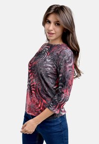 Langarmshirt mit einem wirbelnden abstrakten Muster in Rot, Schwarz und Grau. Der Stoff hat eine glatte Textur mit leichtem Glanz. Runde Ausschnitt.