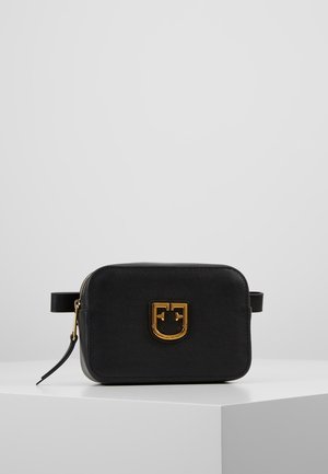 Czarna prostokątna skórzana torba z emblematem logo w kolorze złotym na przedniej stronie, zamknięciem na zamek błyskawiczny oraz regulowanym bocznym paskiem, na białym tle.