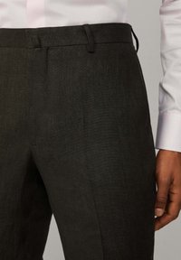 Pantaloni grigi scuri su misura con una texture liscia, caratterizzati da una vita piana, tasche laterali e un design a taglio slim.