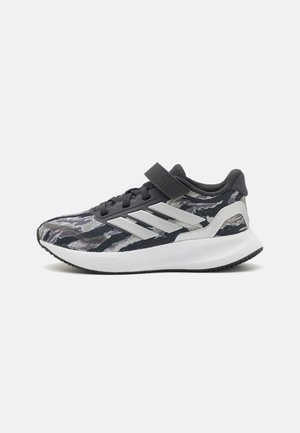 Scarpa sportiva con tomaia in tessuto camo blu navy e grigio, chiusura con cinturino nero e suola in gomma bianca e nera. Accenti argentati sui lati.