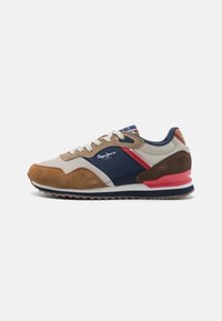 Sneaker featuring a mix of beige, brown, and navy blue materials, smooth and suede textures, with a pink heel accent and white laces.
