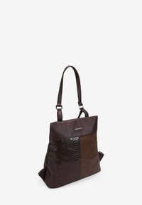 El bolso de mano de cuero marrón presenta una combinación de paneles lisos, de ante y texturizados con un acento brillante. Incluye una correa de hombro ajustable.