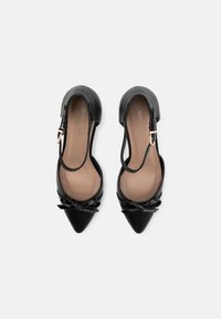 Black leather pointed-toe shoes with a glossy finish, featuring a bow detail at the front and a slingback strap with a gold buckle.