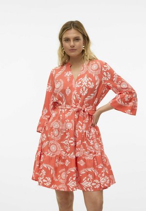 Koraalrood jurkje met wit bloemenpatroon, V-hals, lange mouwen en een cinched taille. Met een gelaagde rok en zachte, lichtgewicht stof.