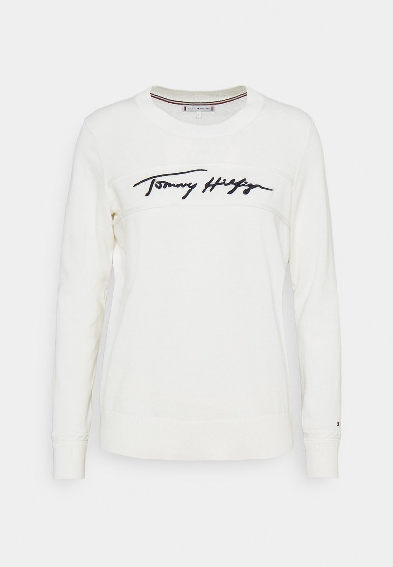 Sweat-shirt blanc à manches longues avec col rond et logo "Tommy Hilfiger" en cursive noire sur la poitrine.