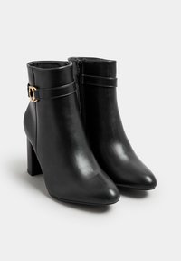 Botas de tobillo de cuero negro con punta afilada, que presentan una hebilla de acento dorado y un cierre de cremallera lateral. Diseño de tacón cuadrado para mayor estabilidad.