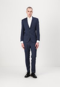 Navy blue suit with a tailored design, featuring a single-button jacket and flat-front pants, complemented by a white dress shirt and black shoes.