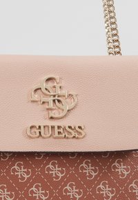 Borsa a tracolla in pelle sintetica rosa con hardware dorato, caratterizzata da un dettaglio del logo e una base marrone testurizzata con un motivo ripetuto.