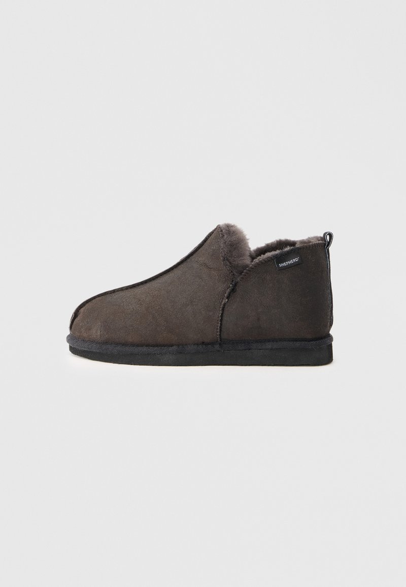 Dark brown suede slipper with soft fur lining, low ankle height, flat black sole, and a small "Shepherd" label on the heel side.