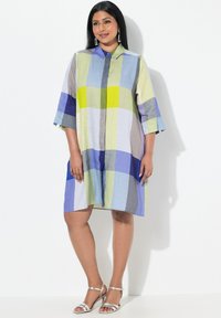 Abito camicia con un design a patchwork multicolore composto da quadrati verdi, blu, grigi e viola. Realizzato in tessuto leggero, con maniche a tre quarti.