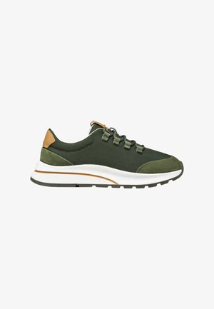 Zapatilla verde de corte bajo con parte superior de malla y ante, lengüeta de cuero marrón claro en el talón, suela blanca con detalle marrón y cierre con cordones.