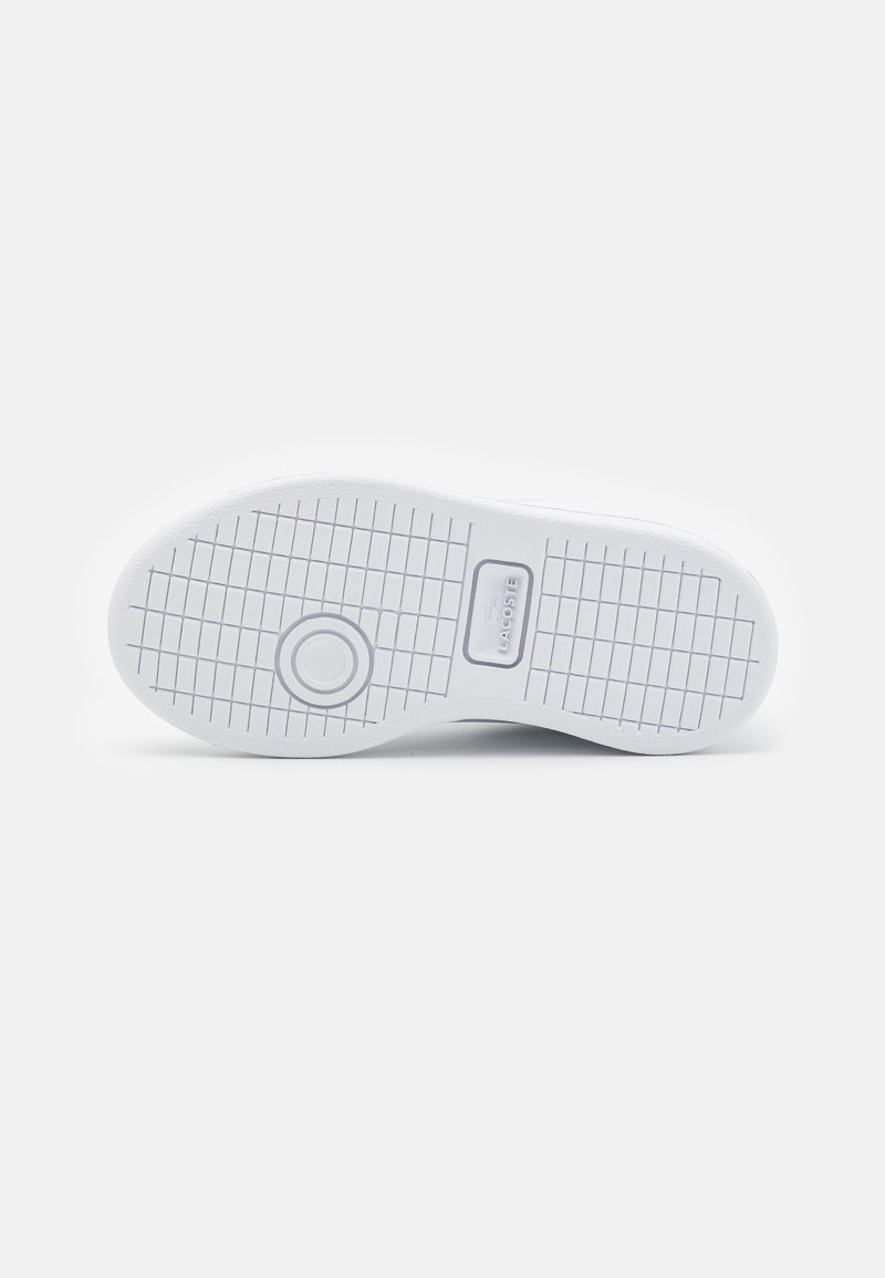 Semelle de sneaker blanche avec un motif de grip texturé, présentant un emblème rond et un détail de logo, fabriquée à partir d'un matériau en caoutchouc durable.