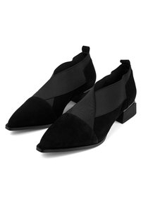 Pari mustia mokkanahkaisia teräväkärkisiä nilkkureita, joissa on leveät joustavat ristisidokset ja matalat lohkokorot.