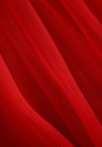 Czerwona, przejrzysta tkanina z delikatnymi, płynącymi plisami. Tekstura wydaje się lekka i przewiewna, z gładkim wykończeniem i subtelną głębią.