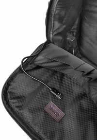 Czarna torba podróżna z siatkowym wnętrzem, wyposażona w kabel USB i brązową skórzaną metkę. Materiał ma wzór kratki.