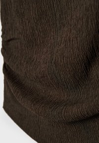 Tissu brun foncé avec une surface texturée et froissée, présentant de subtils motifs ondulés verticaux.