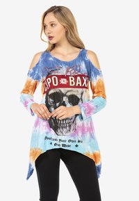 Langärmliges, batikfarbenes Oberteil in Blau, Orange und Pink mit kalten Schultern. Mit einem Totenkopf-Graphic und Text darunter in schwarzen und roten Strasssteinen.