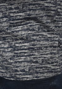 Crewneck-top med et marineblått og grått abstrakt stripe mønster, laget av mykt stoff med en lett teksturert overflate.