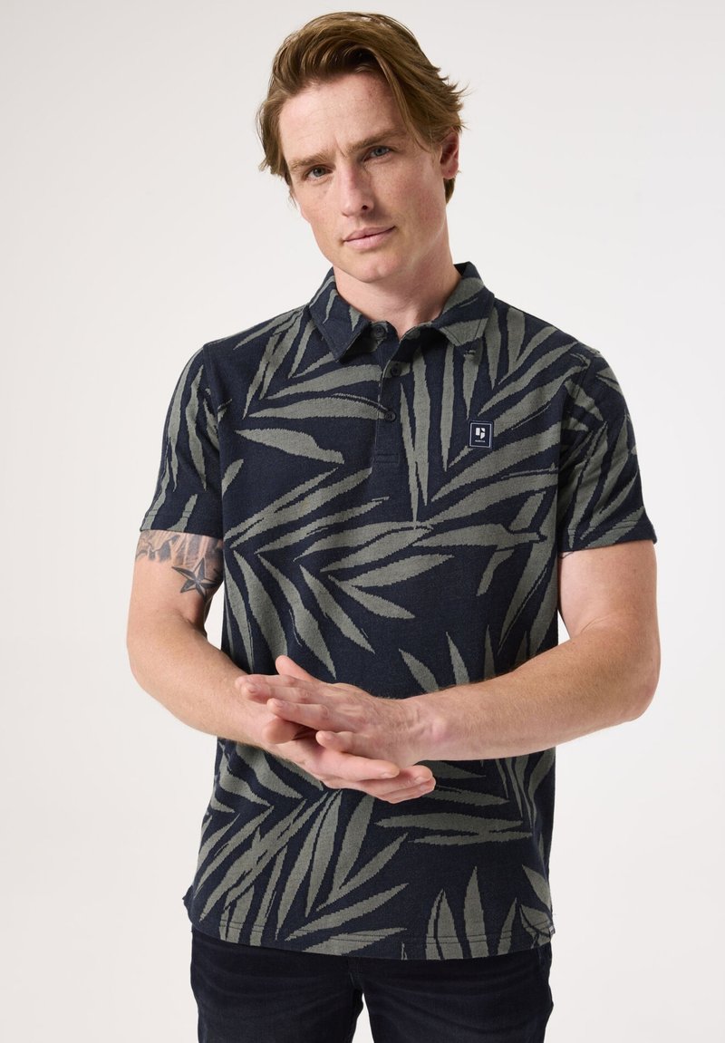 Marineblaues Poloshirt mit grünem Blattmuster, kurzen Ärmeln und einem Kragen. Verfügt über ein kleines Logo auf der linken Brust.