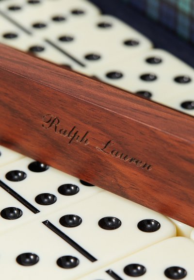 Set di domino in legno con incisione "Ralph Lauren" su un supporto marrone. I domino sono di colore crema con punti e linee nere.