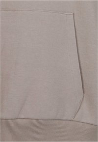 Lichtbeige hoodie met een kangoeroezak. De stof heeft een getextureerd uiterlijk met een geribde tailleband en manchetten. Naaiseams zijn zichtbaar bij de zak.