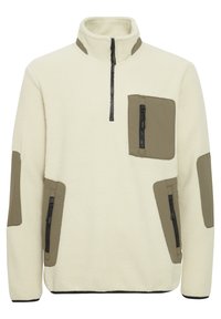 Fleece pullover in off-white with olive green accents. Features a half zipper, chest pocket, and zippered side pockets. Textured fabric.