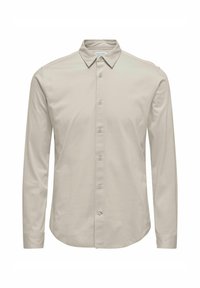 Camisa de manga larga en beige claro, de material de algodón suave. Presenta un cuello clásico y un cierre de botones en la parte delantera con seis botones.