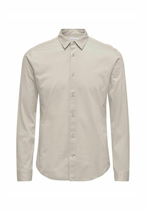 Camisa de manga larga en beige claro, de material de algodón suave. Presenta un cuello clásico y un cierre de botones en la parte delantera con seis botones.