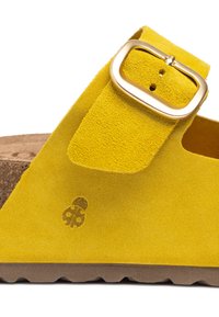 Sandale en suede jaune avec un coussin en liège, dotée d'une boucle en métal doré et d'un logo frappé sur le côté. Semelle en caoutchouc rainurée pour une meilleure adhérence.
