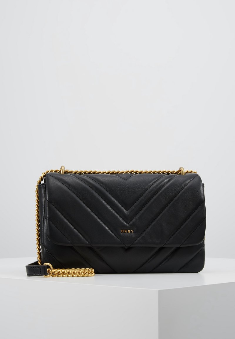 Czarna pikowana skórzana torebka z wzorem jodełki, złotym łańcuszkiem i logo na plakietce. Kompaktowy, prostokątny kształt z gładką fakturą.