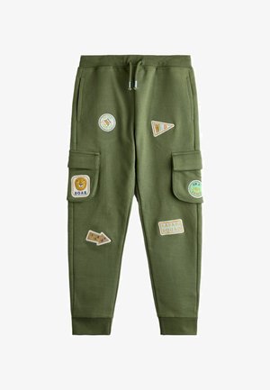 Zielone spodnie typu cargo dla dzieci z sznurkiem w pasie oraz naszywkami przedstawiającymi lwa, strzały i hasła takie jak "ROAR" i "SAFARI SQUAD".