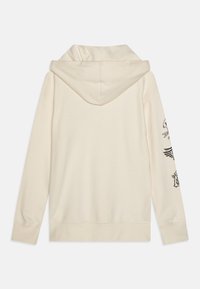 Lichtbeige hoodie met een capuchon met trekkoord, lange mouwen en zwarte grafische ontwerpen op de linkerarm. Zachte stoftextuur.