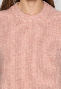 Jasnoróżowy, dziergany sweter o prążkowanej fakturze, z okrągłym dekoltem i bez widocznych wzorów ani elementów ozdobnych.