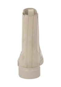 Botín de ante beige con textura suave, paneles laterales elásticos, diseño minimalista y tacón bajo. Detalle del logo en la parte trasera.