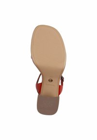 Röd klacksandaler med en slät läderövre. Sulan är beige med ett texturerat greppmönster och präglandet varumärkeslogotyp.