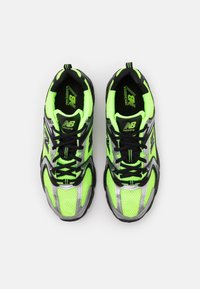 Neon gröna löparskor med svarta accenter, andningsbart mesh-överdrag, silverdetaljer och svarta snörning. Har en dämpad sula.