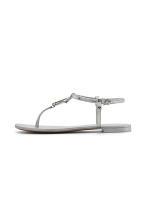 Zilveren platte sandaal met dunne bandjes, enkelgesp en een klein decoratief juweel op de T-band, zijaanzicht op witte achtergrond.
