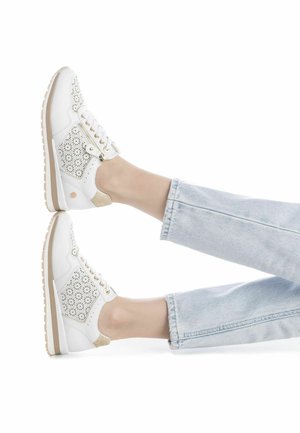 Zapatilla blanca con recortes florales en los laterales, acentos dorados y detalles en beige. Suela media texturizada y cordones planos con cierre de cremallera.
