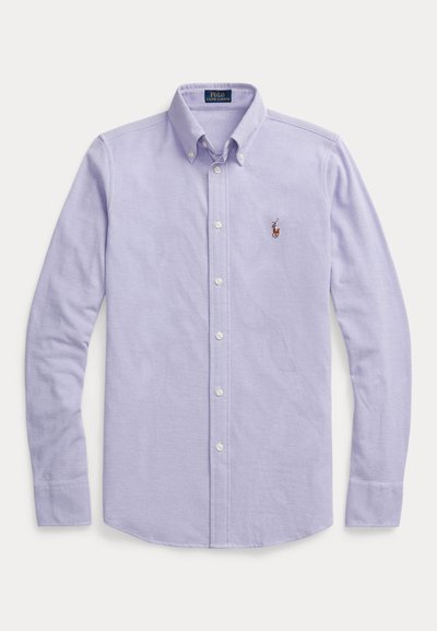 Light purple long-sleeve button-up shirt made of cotton. Features a classic collar, white buttons, and a small embroidered logo on the chest.