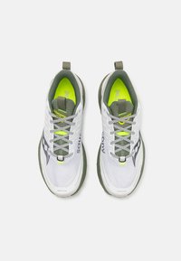 Scarpe da ginnastica bianche con accenti verdi, tomaia in rete, suola testurizzata, elementi riflettenti e foderatura interna verde e gialla.