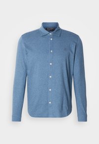 Camisa polo azul de manga comprida feita de tecido texturizado, com frente abotoada e um pequeno logótipo no peito.