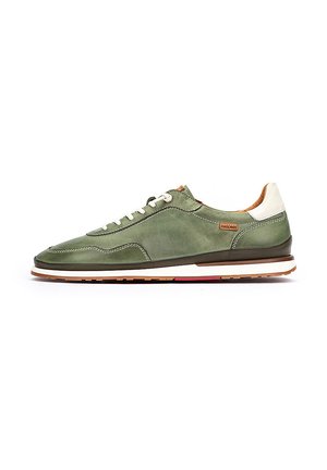 Baskets en cuir vert à profil bas, avec un accent blanc au talon et une semelle beige. Équipées de lacets blancs et de détails de couture visibles.
